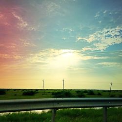 Scenic view of grassy field against sky at sunset