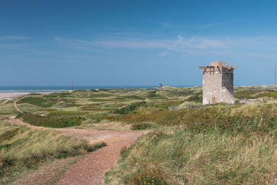 Lighthouse on landscape against sky