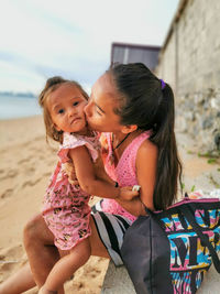 Happy mother kiss her little baby girl and looking at camera