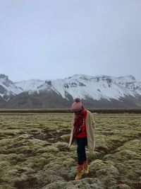 Rear view of man standing on snowcapped mountain against sky