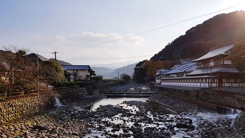 Houses by river against sky during winter