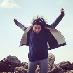 Full length of girl standing on rock against sky