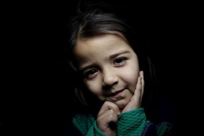 Portrait of cute girl against black background