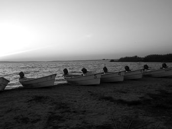 People on boats moored in sea against sky