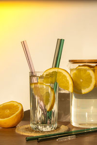 Glass of water with fresh lemon juice with reusable glass straws detox cold tonic water with sunny