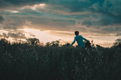 Man on field against sky during sunset