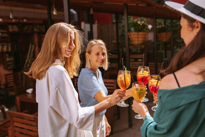 Young woman holding glass while standing outdoors