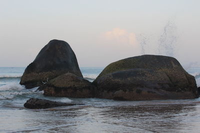 Rock formation in sea against sky