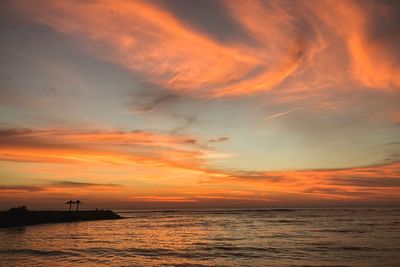 Scenic view of sea against dramatic sky during sunset