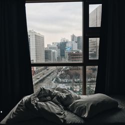 Buildings against sky in city seen through glass window