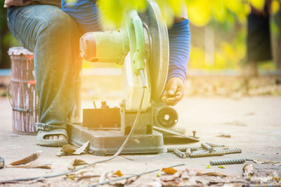 Low section of worker using rotary saw outdoors