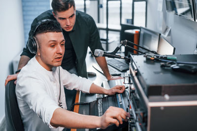 Conception of teamwork. two guys is indoors in the radio studio is busy by broadcast.