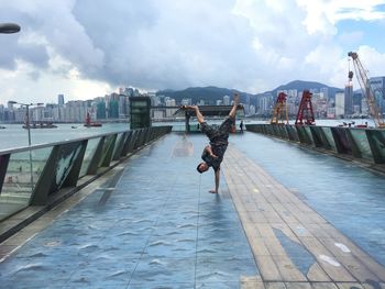 Rear view of woman walking on bridge against cloudy sky