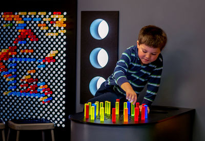 Child plays with colorful pegs against a lit grid, at a children's museum