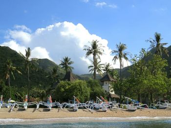 Outrigger boats at beach by mountains against sky