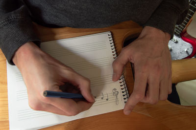 Midsection of man holding mobile phone on table