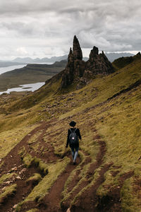 Rear view of man climbing on mountain against sky