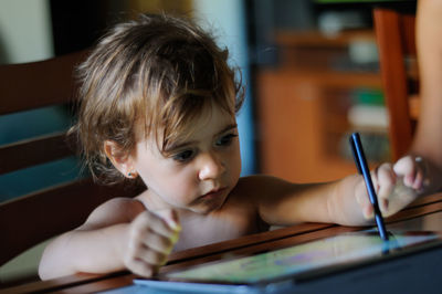 Cute baby girl with digital tablet on table