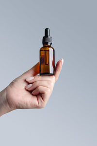 Close-up of hand holding bottle against white background