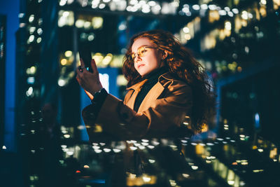Portrait of young woman standing against sky at night