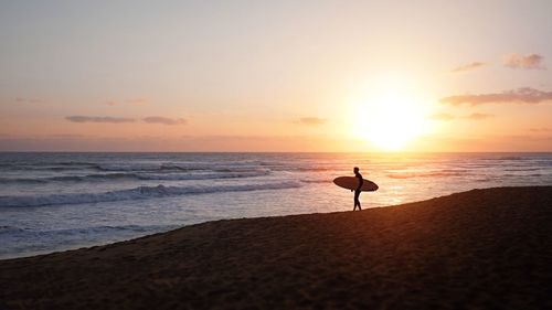 Silhouette man on beach against sky during sunset