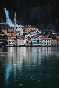 Scenic view of lake by buildings in city during winter