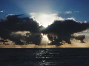 Sunlight streaming through clouds over sea