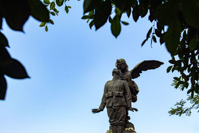 Low angle view of angel statue against clear blue sky