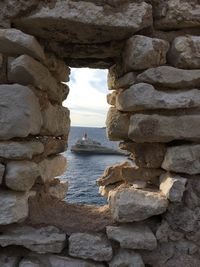 Stone wall by sea against sky