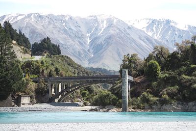 Bridge over river by mountains against sky