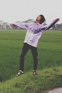 Young man with arms outstretched jumping at farm