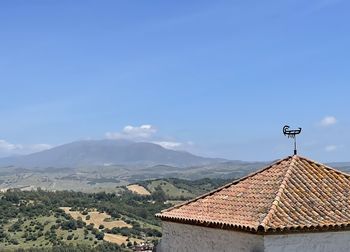 Scenic view of building and mountains against blue sky