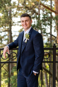 Handsome young groom wearing elegant and stylish dark blue suit outdoors portrait. 