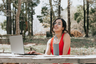 Young woman using mobile phone while sitting at park