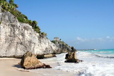 Rock formation on beach against sky