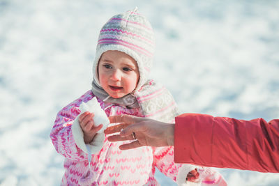 Portrait of cute girl holding hat during winter