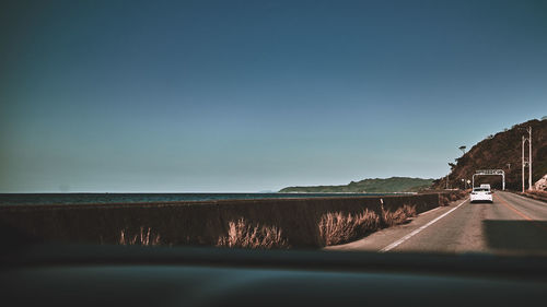 Road by sea seen through car windshield