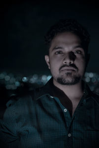 Portrait of young man against black background