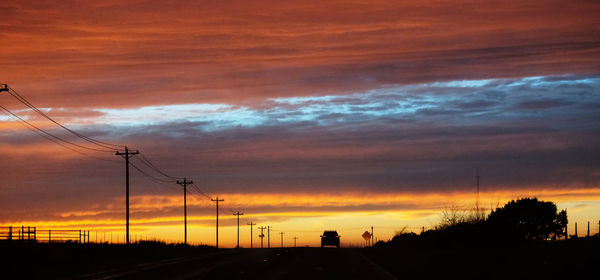 Silhouette electricity pylon against sky during sunset