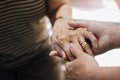 Cropped image of elderly care nurse holding hand of senior woman at nursing home