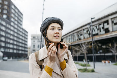 Portrait of woman putting on bicycle helmet in the city