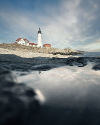 Lighthouse by sea against sky