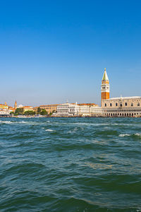 View of sea and buildings against clear blue sky