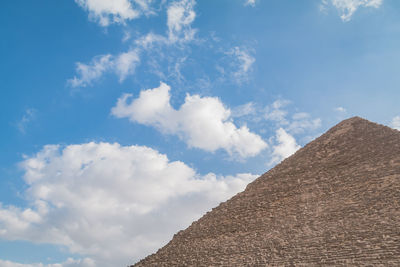 Low angle view of pyramid against cloudy sky