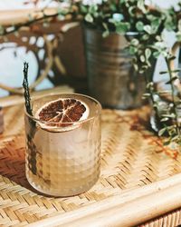 Close-up of yellow clear drink on boho shelf with potted plant