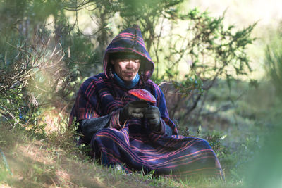 Colombian native american man in traditional clothing collecting mushrooms