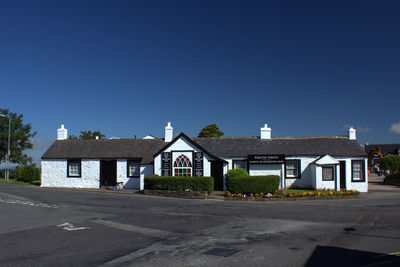 Building by road against clear blue sky