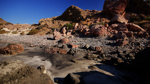 Scenic view of rocks on field against clear blue sky