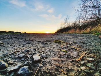 Surface level of land against sky during sunset
