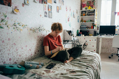 Teenage girl doing homework while sitting in the room.